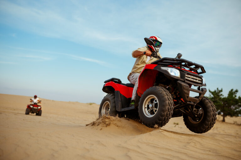 Two men in helmets ride on atv, action view, freedom riding in desert. Male persons on quad bikes, sandy race, dune safari in hot sunny day, 4x4 extreme adventure, quad-biking